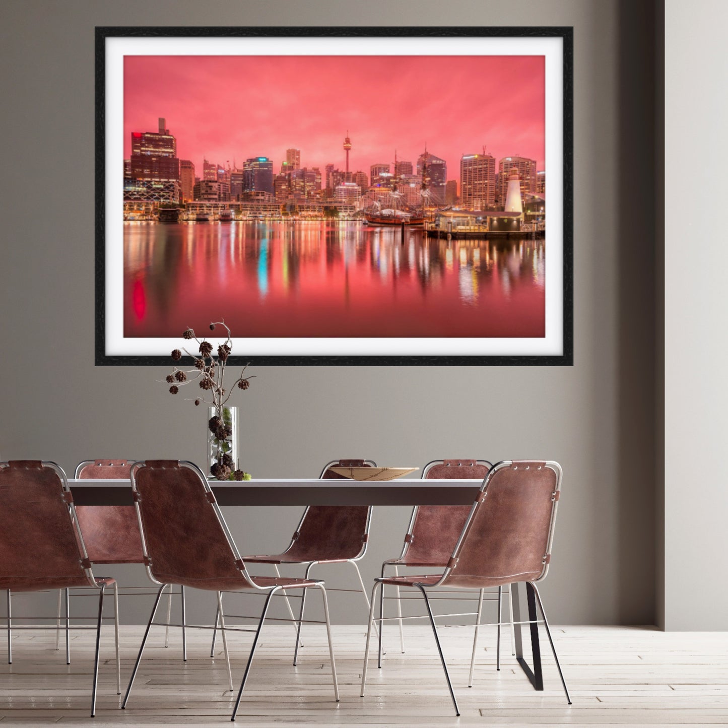 Framed cityscape print in rose pink on a wall above a dining table with chairs.