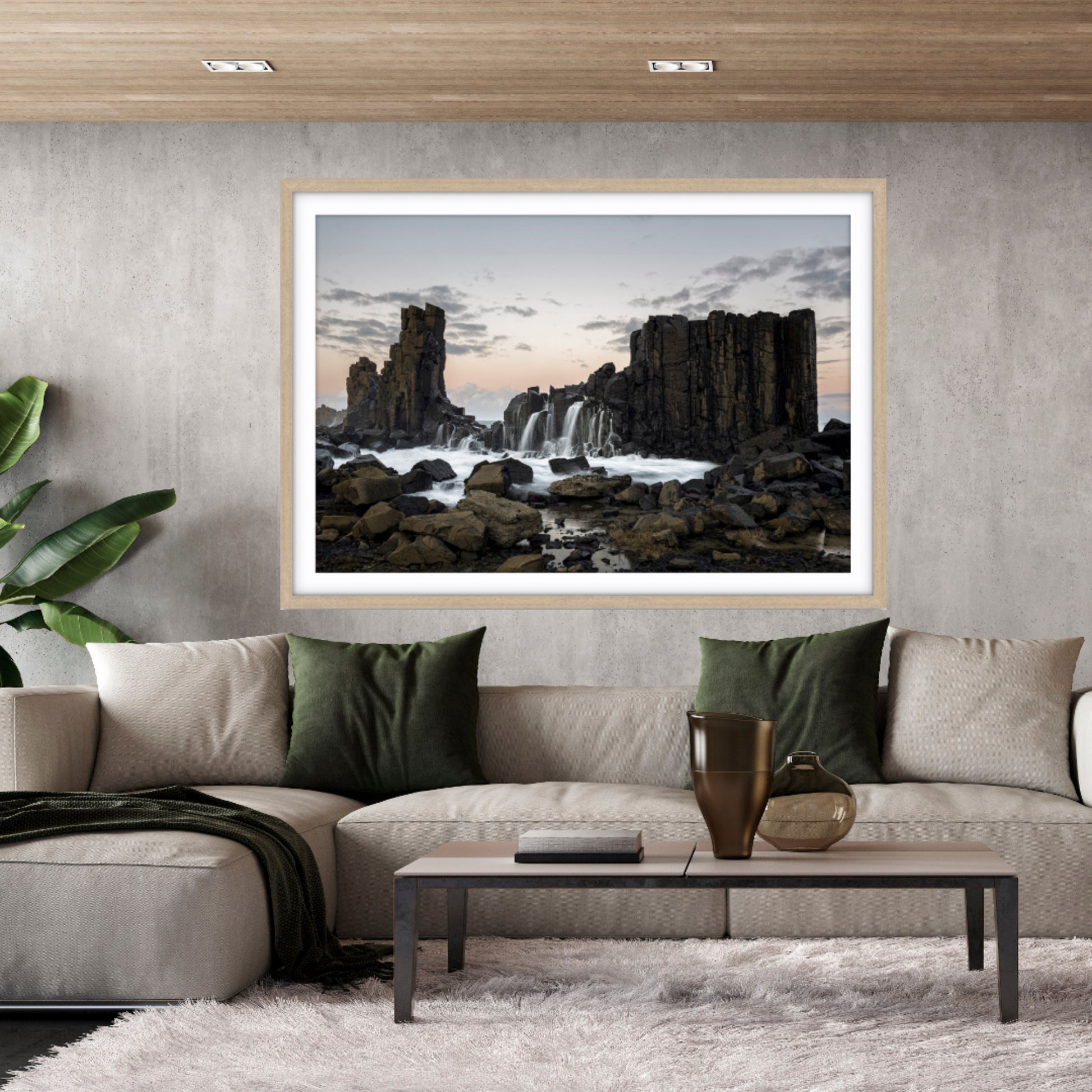 Framed seascape at Bombo Quarry fine art print of a waterfall on a wall above a sofa in a living room.
