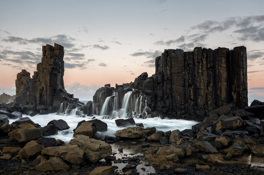 Bombo Quarry waterfall cascade over basalt columns South Coast NSW with dramatic ocean swell at dusk