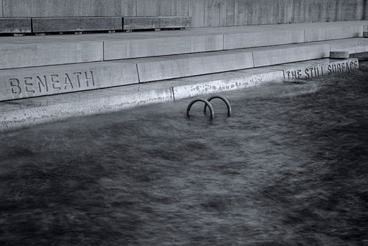 Black and white photograph of still calm water surface with reflections creating contemplative peaceful mood