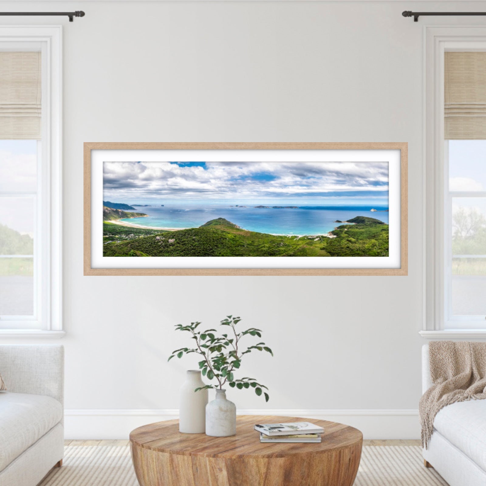 Framed landscape print on a wall in a living room with white walls and furniture.