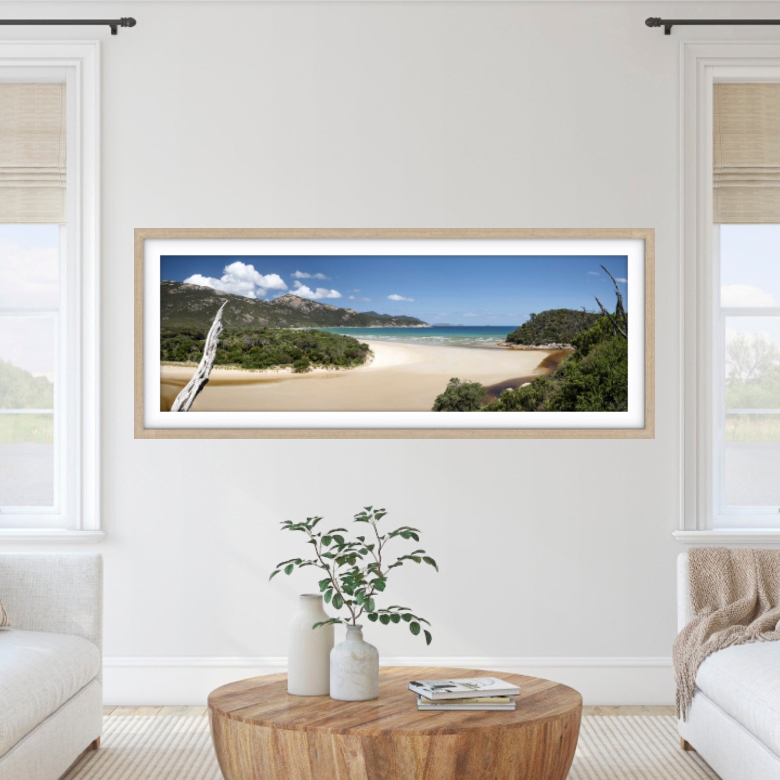 Framed beachscape photography print on a wall in a living room with white walls and furniture.