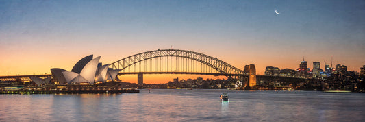 Color photograph of motor cruiser and Manly ferry Sydney Harbour with Opera House and Harbour Bridge sunset