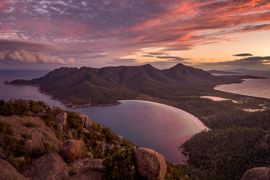 Wineglass Bay Tasmania from Mt Amos summit with golden sunset light over crescent beach and turquoise water