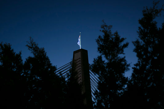 Color photograph Australian flag on Anzac Bridge memorial pylon blue hour sky stars Sydney