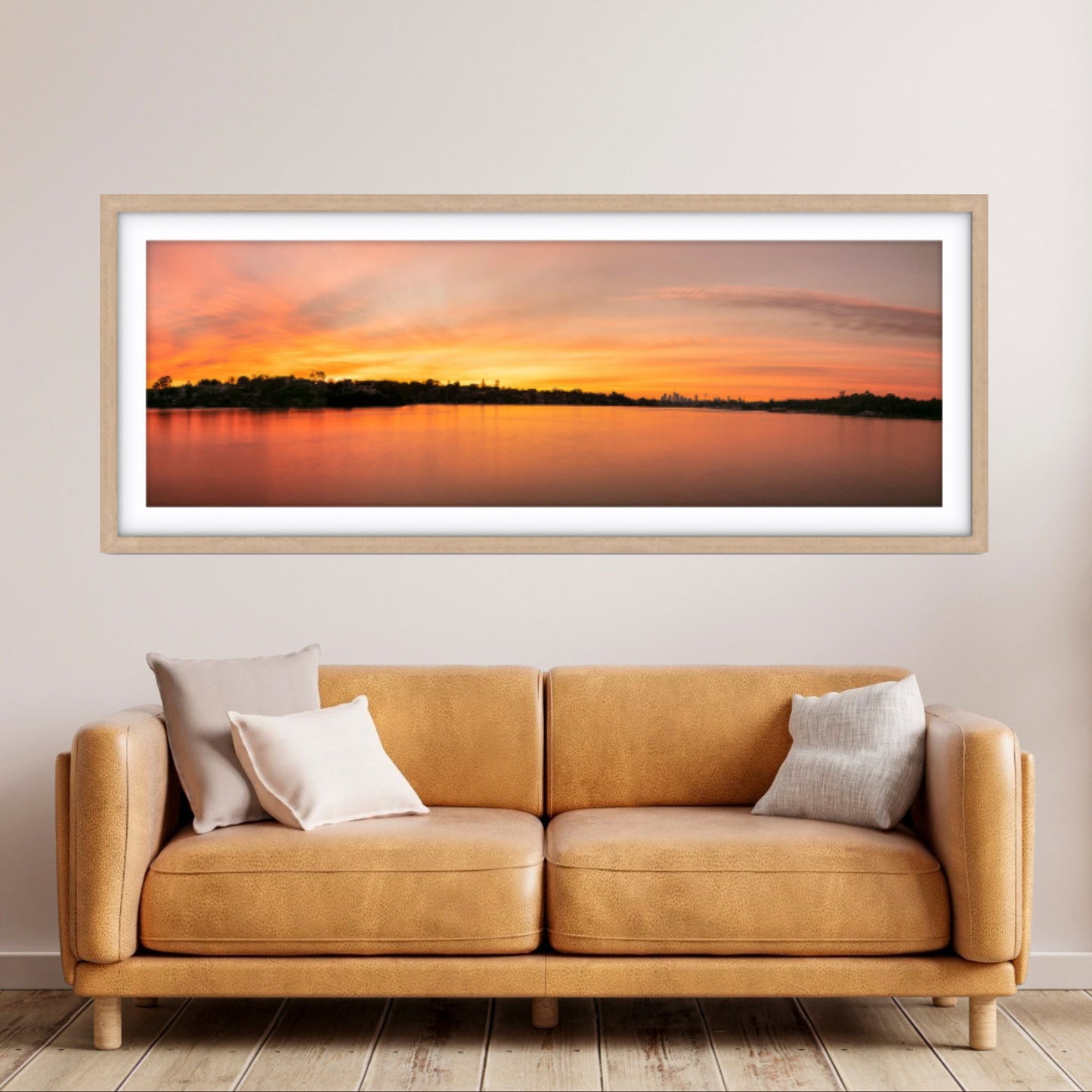 Framed sunset landscape above a beige sofa in a room.