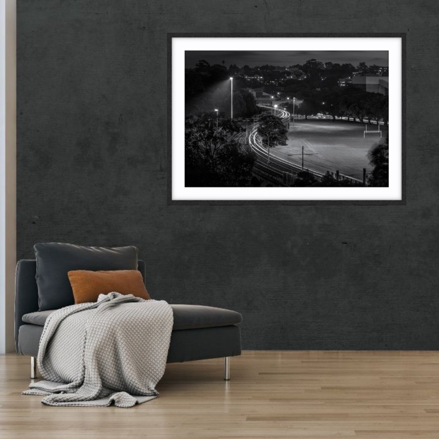 Framed black and white fine art photograph of a light trails at Wentworth Park, Sydney on a wall above a sofa.