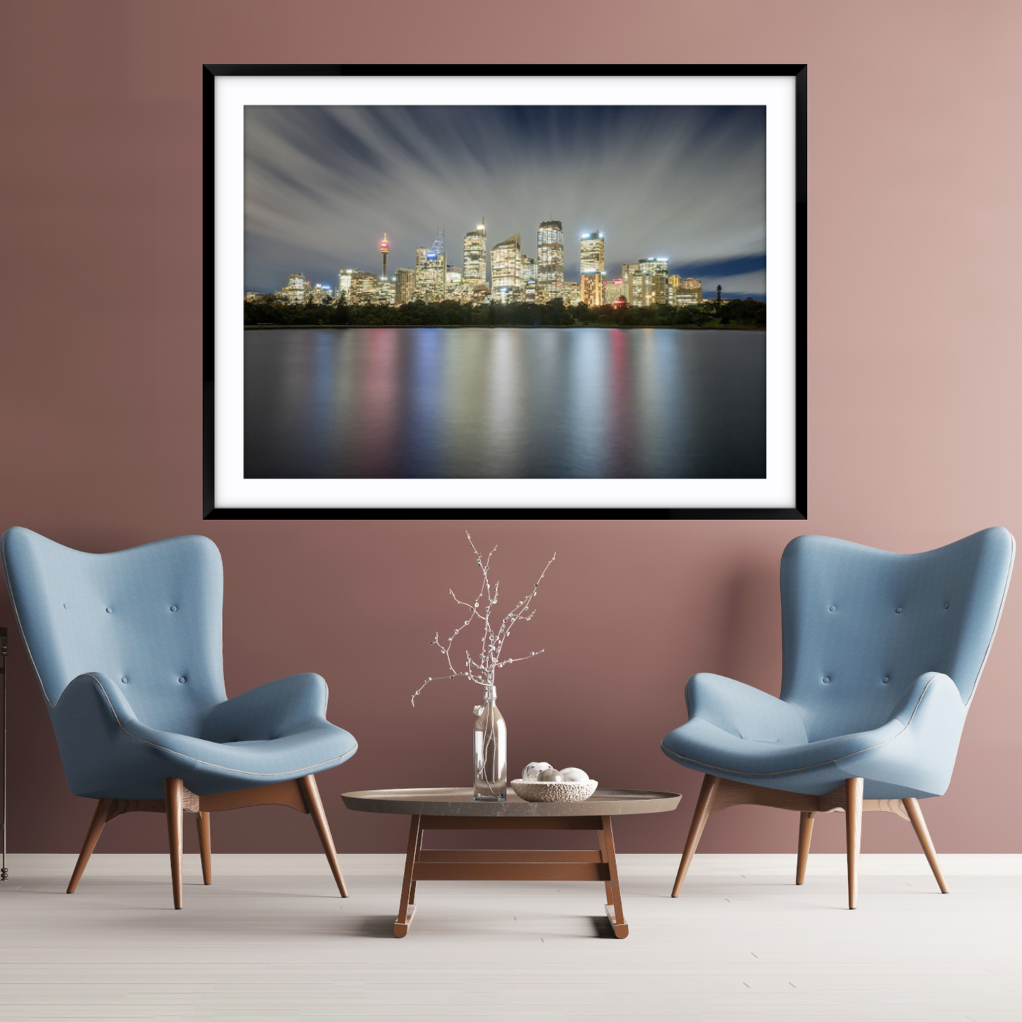 Modern living room with two blue chairs, a coffee table, and a framed cityscape painting on a pinky brown wall.