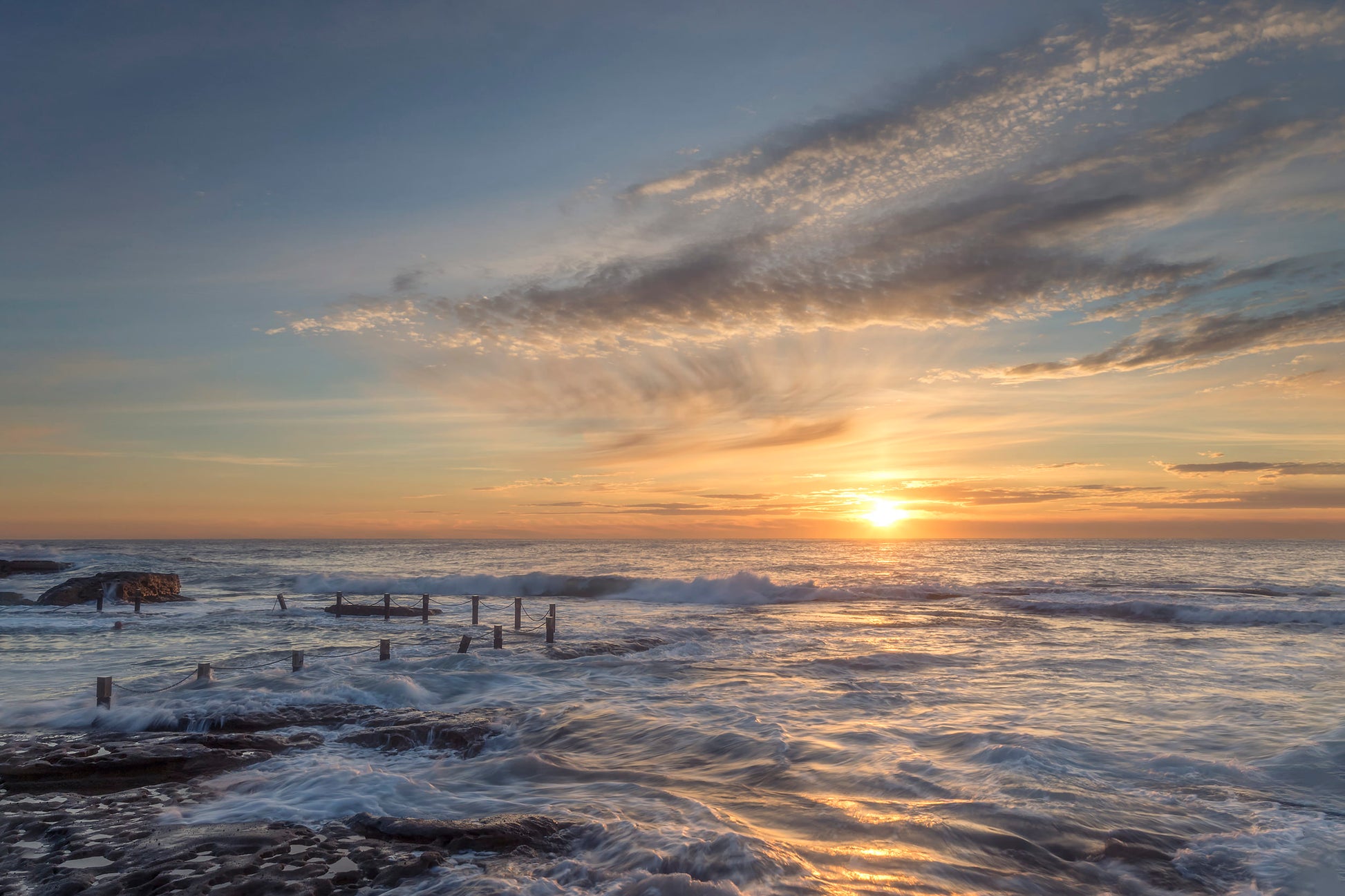 Maroubra Rock Pool Sydney at sunrise with triangular forms reflected in still water and golden sky