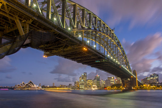 Color long exposure photograph of Sydney Opera House and Harbour Bridge from Milsons Point blue hour ferry wake light trails