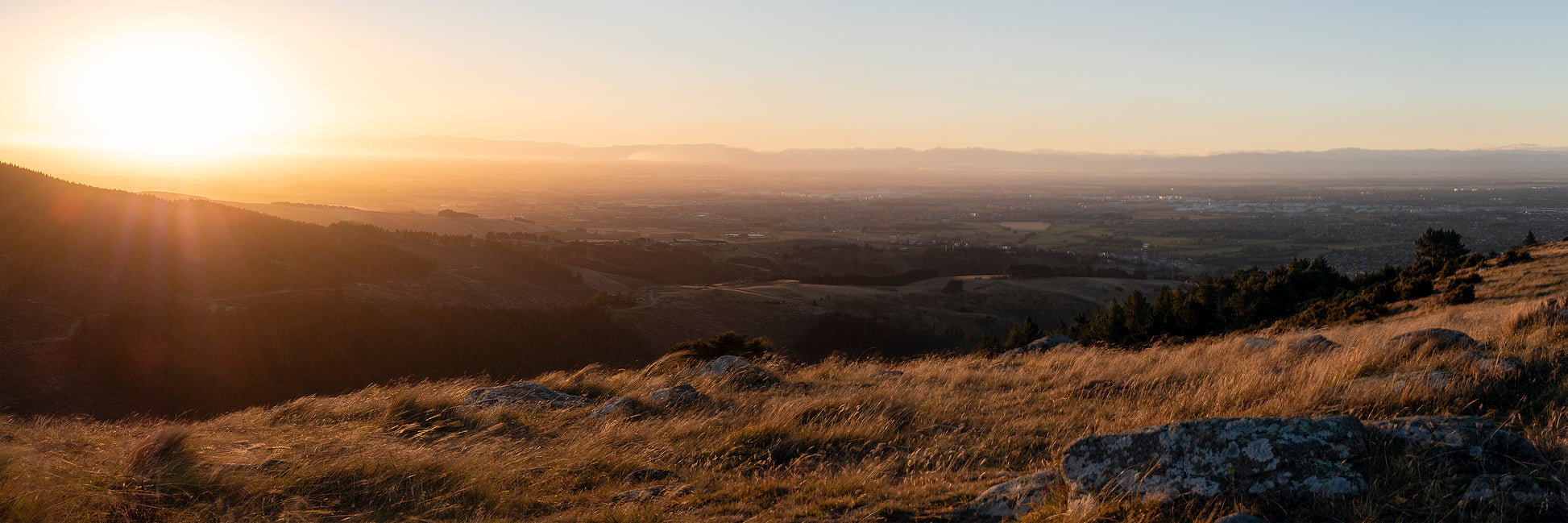Queenstown New Zealand golden hour sunset panorama with rocky foreground overlooking town